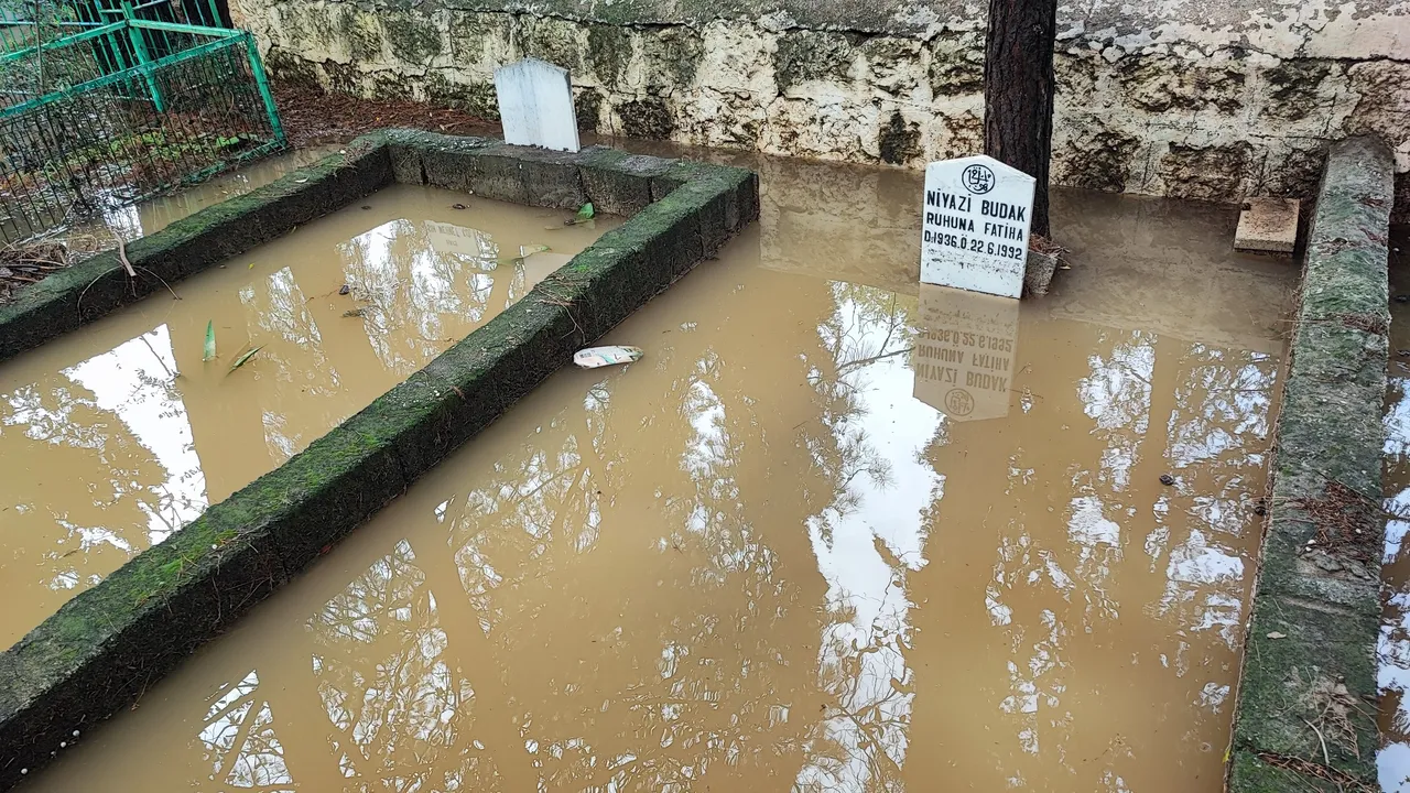 Sağanak yağış mezarlığı göle çevirdi! Poşet geçirip girdiler