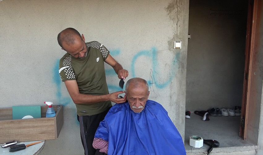 Depremde dükkanı yıkılan berber işini evinin önünde yapıyor
