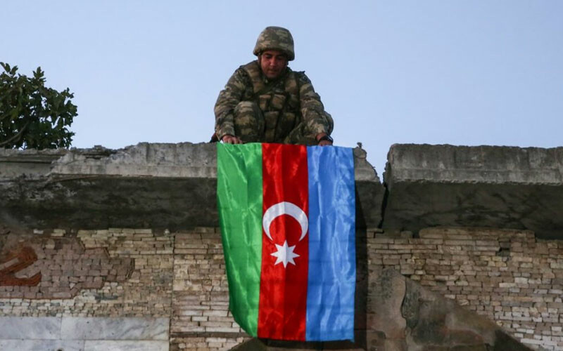 Azerbaycan ordusuna mensup asker, ele geçirilen bölgeye bayrak asıyor