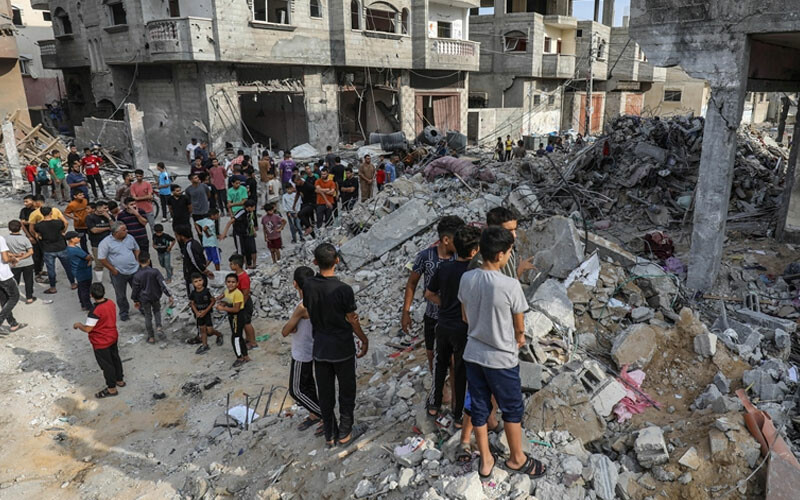 Filistinli siviller, İsrail bombardımanı sonucunda yerle bir olmuş binaları inceliyor