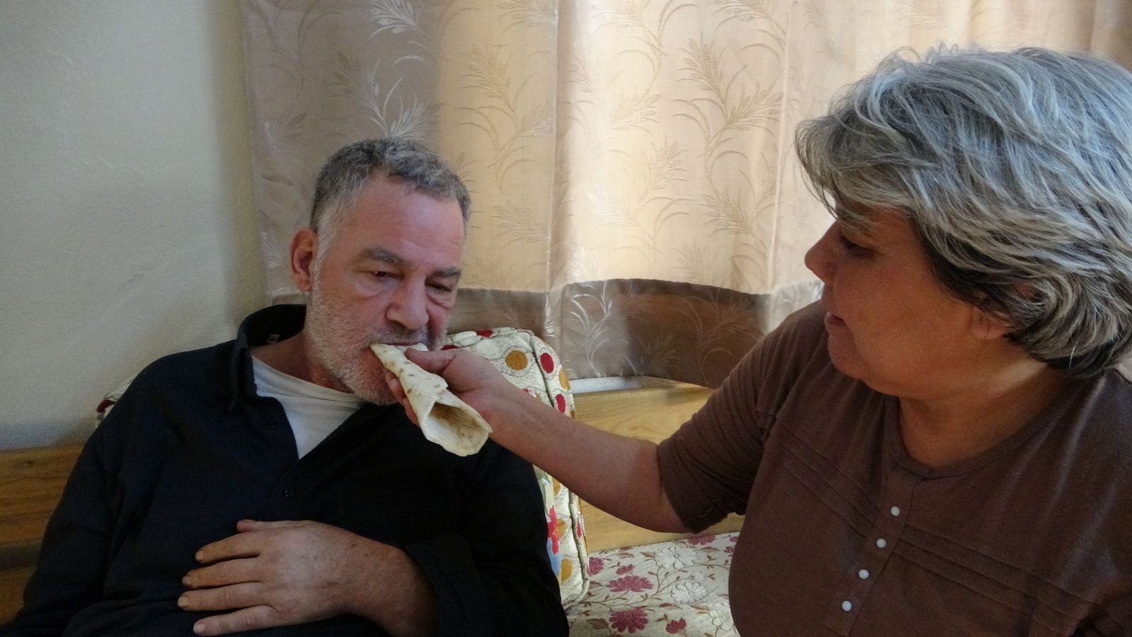 Felçli eşine bebek gibi bakıyor