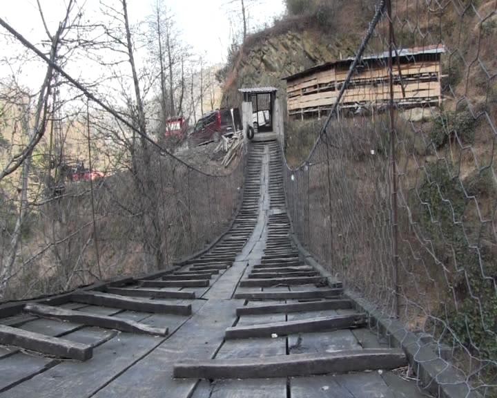 Evine gitmek için demir kapılı asma köprüden geçiyor