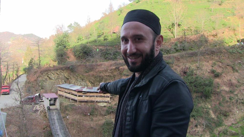 Evine gitmek için demir kapılı asma köprüden geçiyor