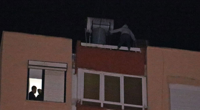 Apartmanın çatısından aşağı sarkan kadını cips yiyerek izlediler