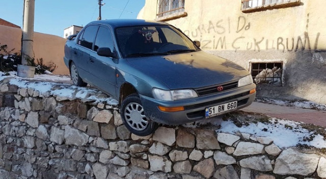 Buzlanmadan dolayı kayan otomobil duvar üzerinde asılı kaldı