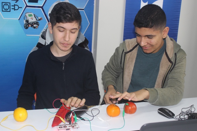 Öğrenciler içi dolu su bardağı ve meyvelerle piyano çalıyor